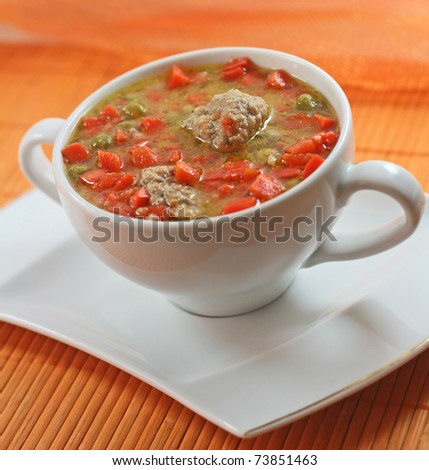 Home-made meatballs and vegetable soup, in a white soup cup