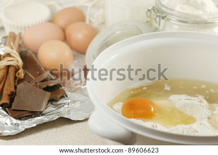 An egg in a pile of flour preparing for baking with kitchen tools