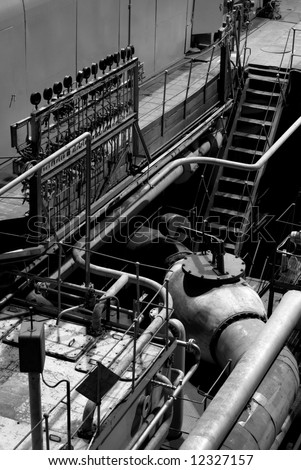 Equipment, cables and piping as found inside of a modern industrial power plant, black and white
