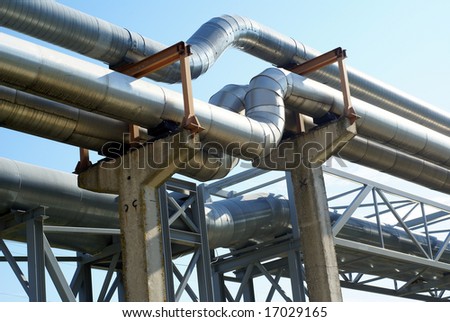 industrial pipelines on pipe-bridge and electric power lines against blue sky