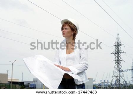 Woman engineer or architect with white safety hat drawings and electrical towers structure on background
