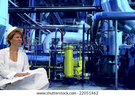 woman engineer, equipment, cables and piping as found inside of a modern industrial power plant