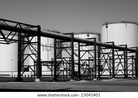 industrial pipelines and storage tanks against blue sky  b&w
