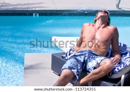 Young Man Sunbathing By pool