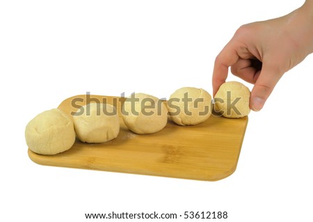 Flour the dough on a wooden board, rolled up into balls. One ball is placed on the board by hand. Isolated on white.