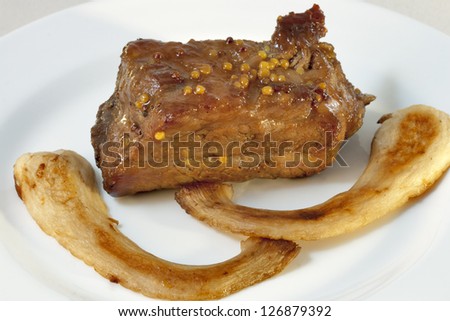 sparerib cooked in mustard and honey sauce with fried king trumpet mushrooms closeup on white plate