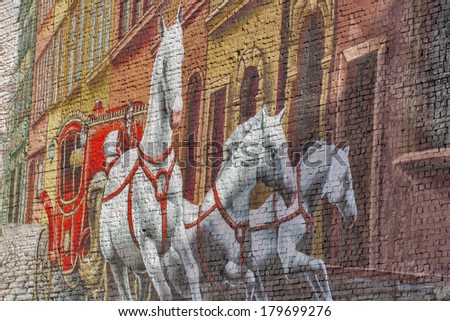 KIEV, UKRAINE - FEBRUARY 18, 2014: Unknown artist street graffiti on building brick wall with red coach and three white horses rushing on the street.