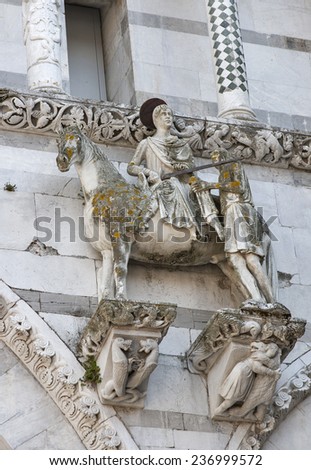 The scene of St. Martin dividing his cloak into two parts and giving one to the poor man on the facade of the Cathedral of St Martin, Lucca, Italy, built in 1070.