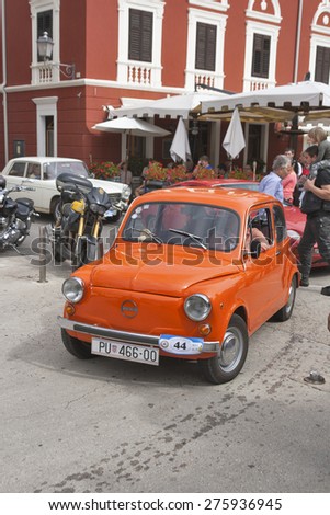 NOVIGRAD, CROATIA - SEPTEMBER 13, 2014: Unrecognizable people watch the parade of vintage cars on the narrow streets on 5th International Old Timer Car Rally organized by club Eppur si muove from Umag