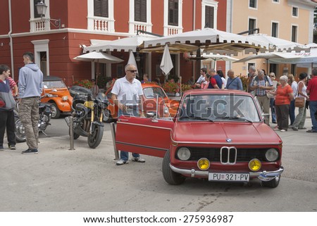 NOVIGRAD, CROATIA - SEPTEMBER 13, 2014: Unrecognizable people watch the parade of vintage cars on 5th International Old Timer Car Rally. The event organized by old timer club Eppur si muove from Umag.
