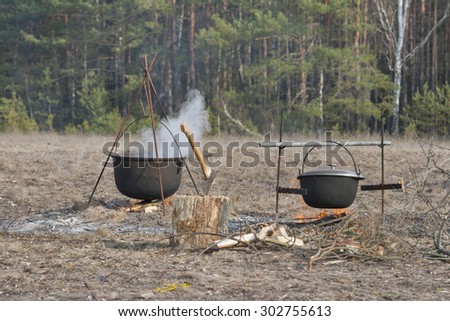cooking food in two large cauldrons on the fire outdoor