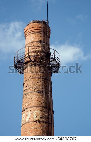 Old brick chimney with lightning rod against a blue sky