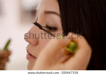Closeup of a makeup artist putting mascara on a client