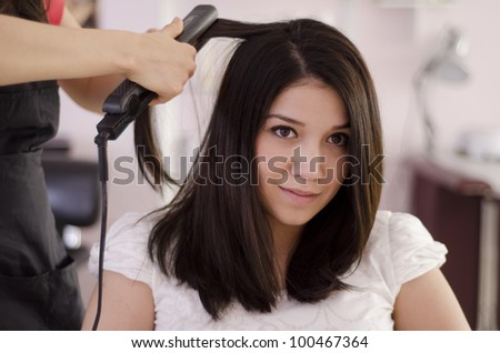 Female hairdresser straightening the hair of a client