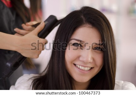 Happy brunette getting her hair straightened