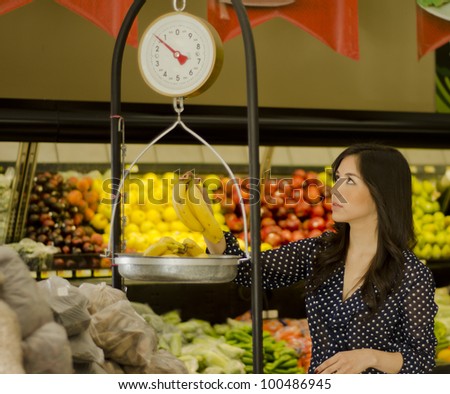 Beautiful latin woman weighing fruits on a scale in a supermarket