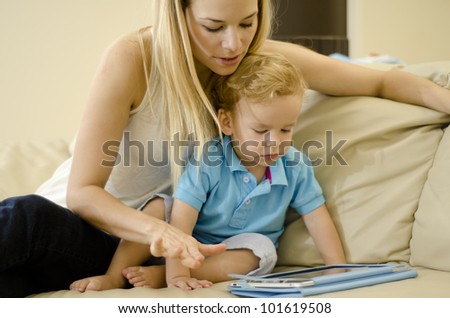 Beautiful caucasian mother playing with her son and a tablet