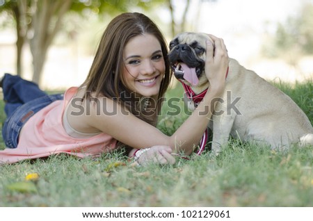 Cute latin woman spending some time with her pug dog at the park