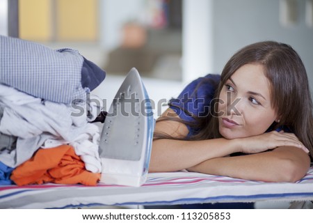 Young housewife overwhelmed for having so many clothes to iron