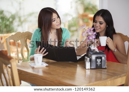 Cute female friends having coffee and getting ready to order at a restaurant