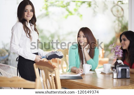 Cute waitress charging customers with a credit card terminal