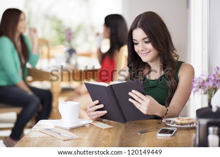 Beautiful young woman enjoying a good book at a coffee shop