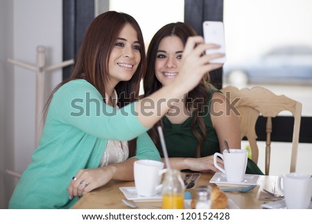 Beautiful latin friends taking a picture with their phone