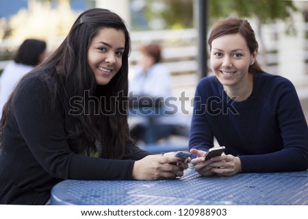 Pretty female students exchanging phone numbers at school