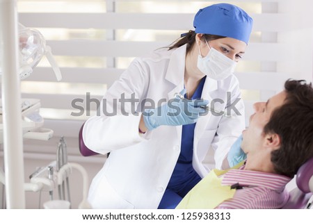 Cute female dentist using some anesthesia on a patient