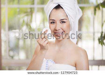Pretty young woman cleansing her face
