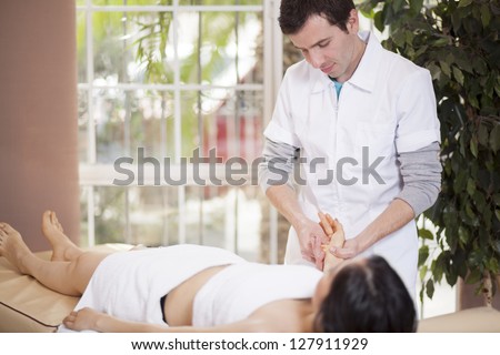 Young latin therapist giving a hand massage to a customer