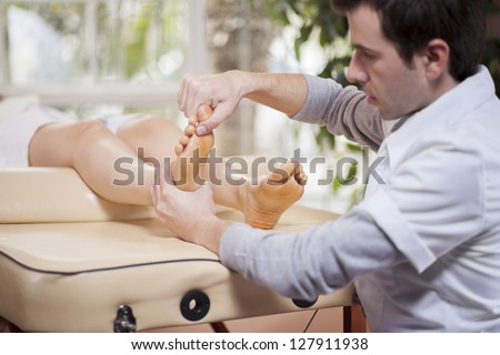 Young latin masseuse giving a foot massage to a client