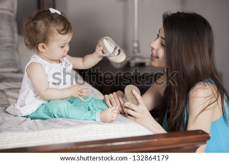 Young latin mom getting her baby girl dressed Young latin mom getting her baby girl dressed