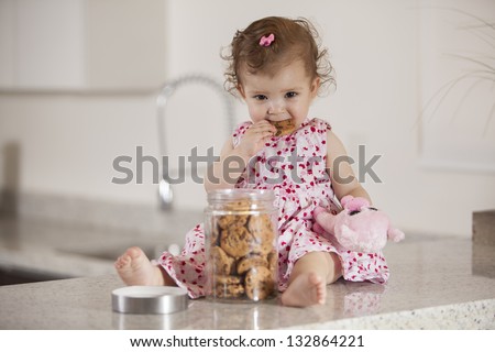 Cute little girl eating cookies from a jar