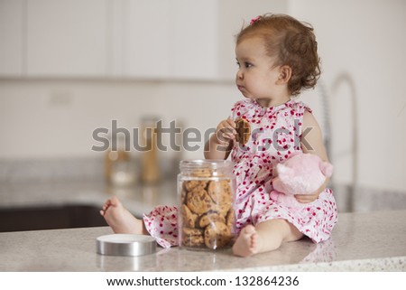 Latin baby girl eating cookies from a jar