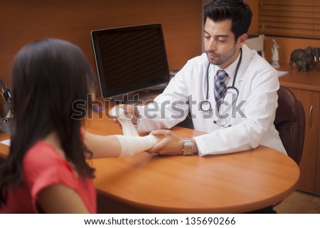 Male doctor putting an arm cast to a patient