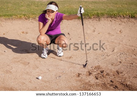 Young female golfer frustrated and stuck in a sand trap