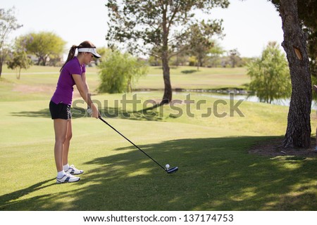 Beautiful Latin golfer concentrating on the ball and ready to swing