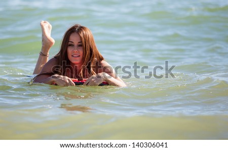 Beautiful Latin girl surfing on a body board at the sea