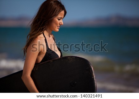 Young beautiful woman holding a body board and ready to surf