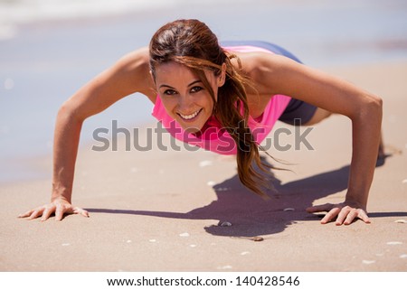 Cute Latin woman exercising and doing some push-ups at the beach