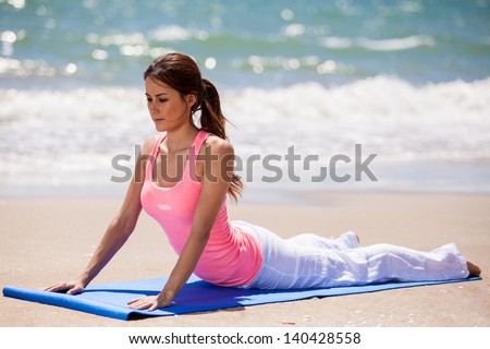 Pretty Latin woman stretching before doing some yoga at the beach