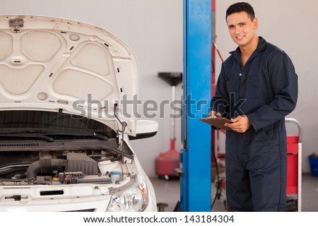 Young handsome mechanic inspecting a vehicle at an auto shop
