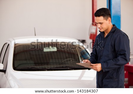 Young mechanic using a checklist to make an initial inspection on a vehicle
