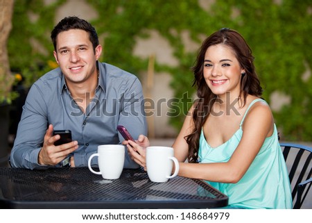 Cute young couple updating their social network status during a date at a cafe