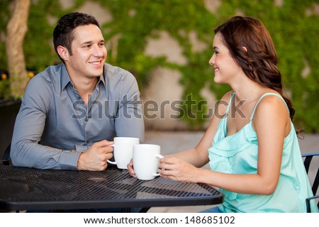 Good Looking Latin Couple Drinking Coffee And Smiling On Their First Date At A Restaurant