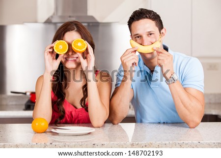 Cute couple playing around with some fruit in the kitchen