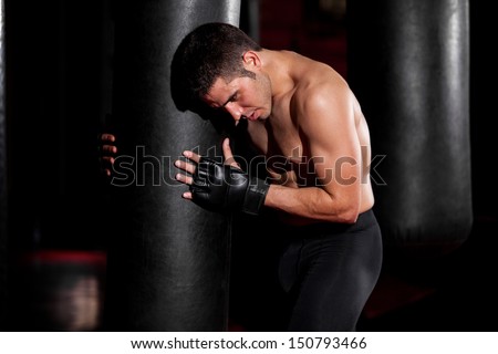 Mixed Martial Arts Fighter getting some air during his training with a punching bag at a gym