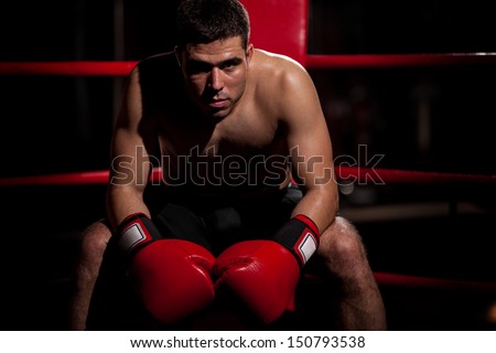 Dramatic portrait of a young Hispanic boxer sitting on his corner of the ring with some copy space
