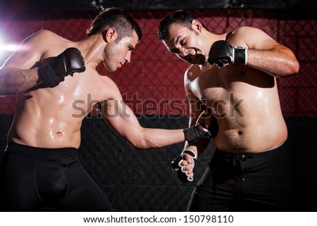 Strong mixed martial arts fighter throwing a punch to his opponent's ribs